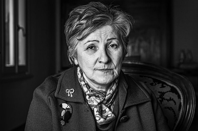 Black and white photograph of Maura Cappi sat looking at camera in her home