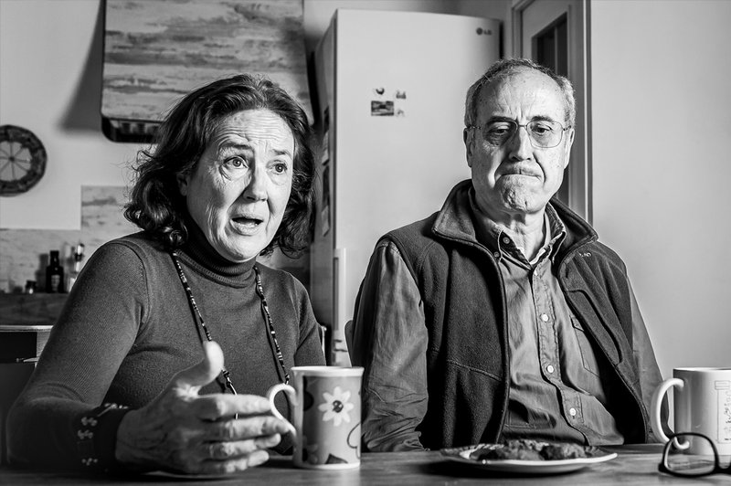 Foto in bianco e nero di una donna e un uomo anziani seduti nella lorom casa (Maria Jose e suo marito) che raccontano la loro storia