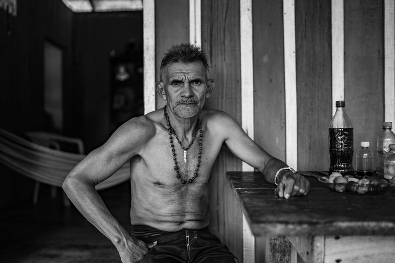 Black and white photograph of Paulo sat in his home telling his story