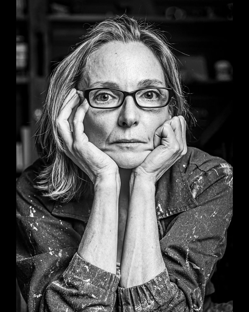 Black and white photograph of Kate Milson looking into camera holding her head in hands