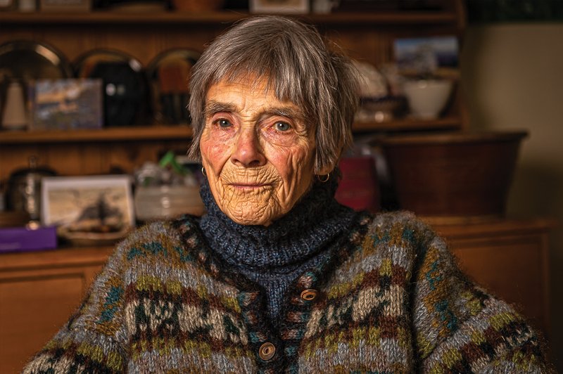 Foto a mezzo busto di una donna anziana (Ros Bradbury) seduta nella sua casa, che guarda nell'obiettivo